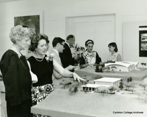 Black and white photo of two women looking at a small model of the building on a table.