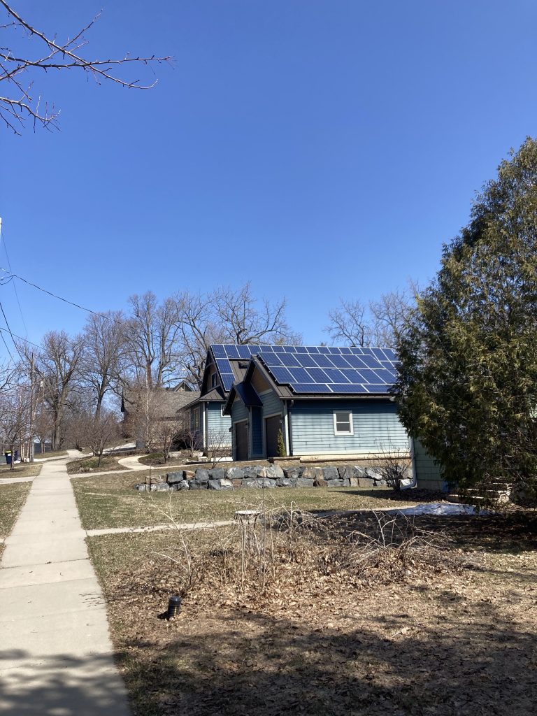 there is a blue house and garge with roofs covered in solar panels