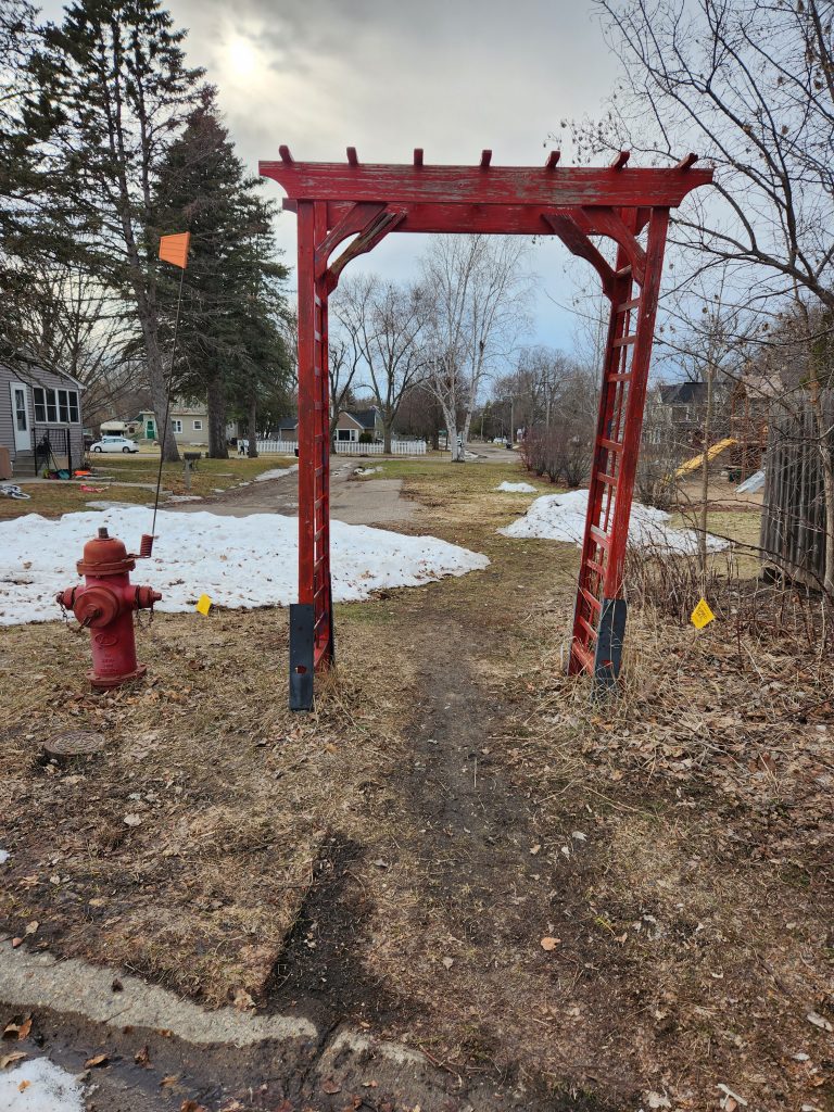 A red garden arch over a path in the neighborhood.