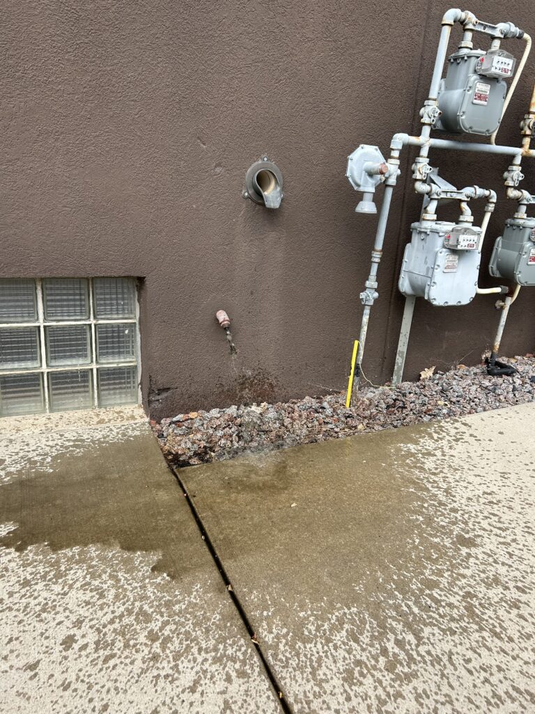 Brown liquid shooting from pipe coming out of wall