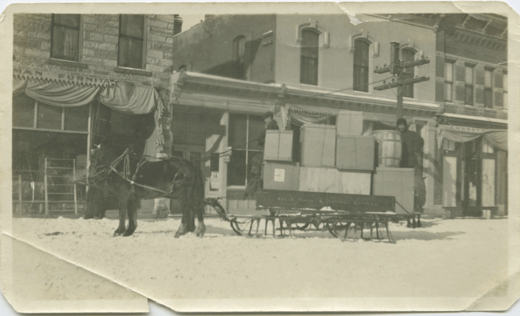 Black and white photograph of a horse pulling a package-laden delivery sled